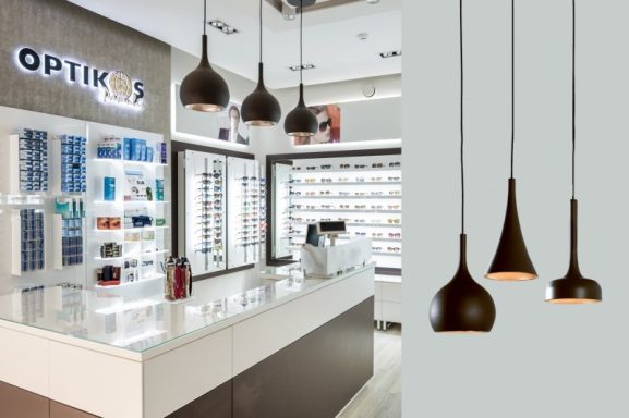 Modern Optiker-Geschäft mit eleganten, hängenden Leuchten und Brillenpräsentation.