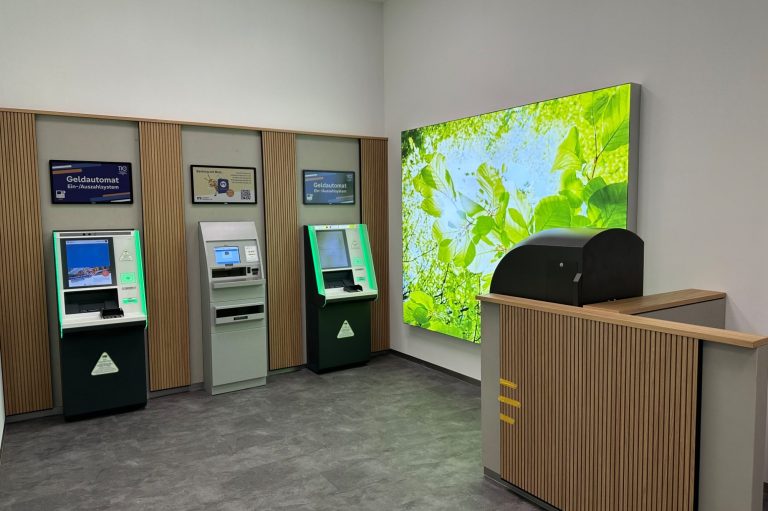 Drei Geldautomaten und ein Postfach in einem modernen Raum mit grüner Wanddekoration.
