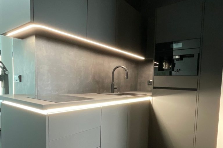 Moderne Küche mit grauen Oberflächen und indirekter LED-Beleuchtung.