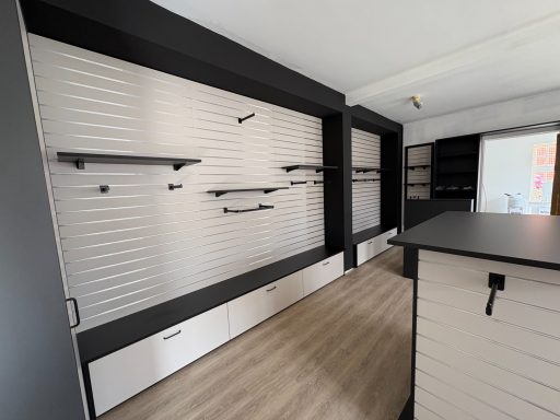 Leere Verkaufswand mit Regalen und Schubladen in einem modernen Verkaufsraum.