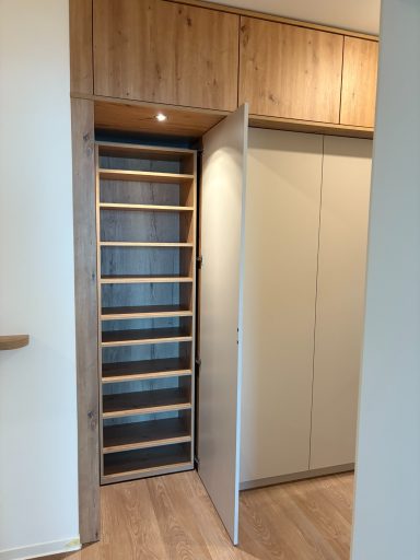 Schrank mit Holzregalen und einer Tür, die zur Seite geöffnet ist.