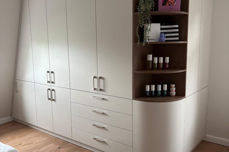 Moderne weiße Möbel mit Schubladen und offenem Regal, in einem hellen Raum.
